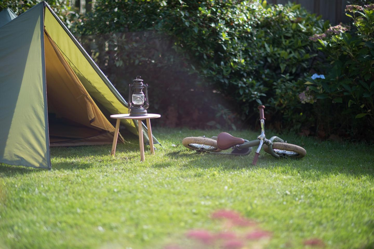 Groene tent met kinderfiets en lantaarn op gras
