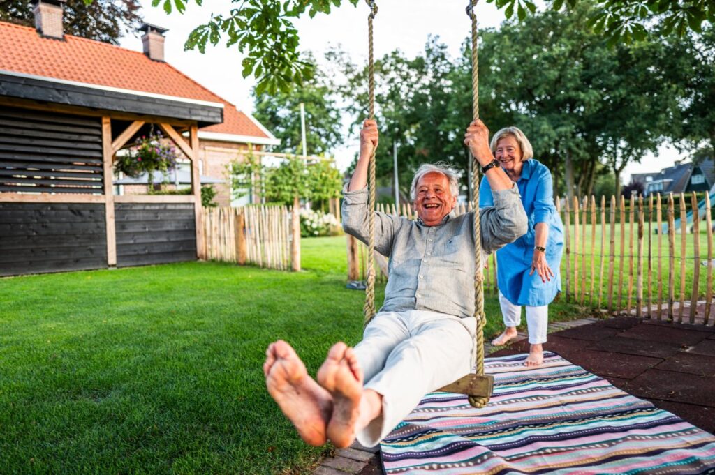 Lachende man op schommel in een tuin met grasmatten