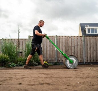 Tuinaannemer walst geëgaliseerde zandgrond aan als voorbereiding op het leggen van grasmatten