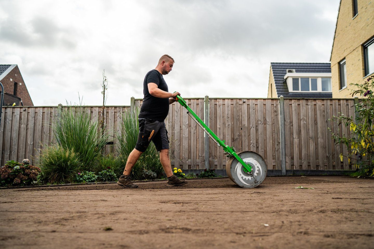 Tuinaannemer walst geëgaliseerde zandgrond aan als voorbereiding op het leggen van grasmatten