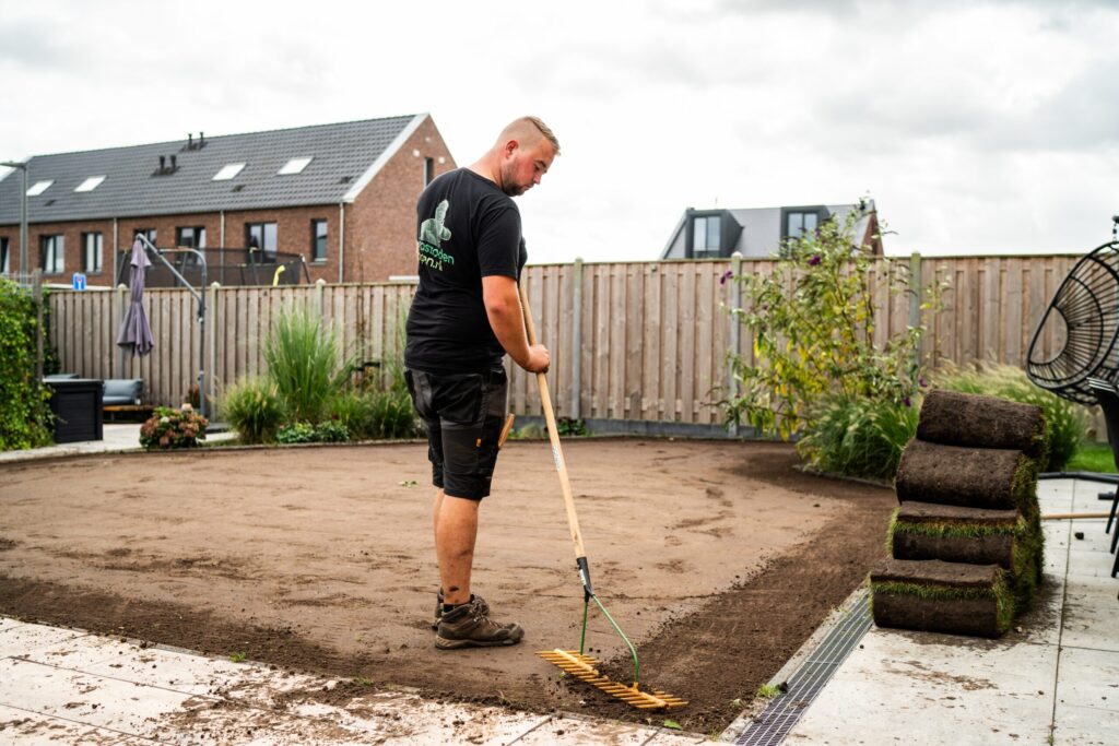 Medewerker egaliseert de ondergrond zorgvuldig ter voorbereiding op het leggen van grasmatten.