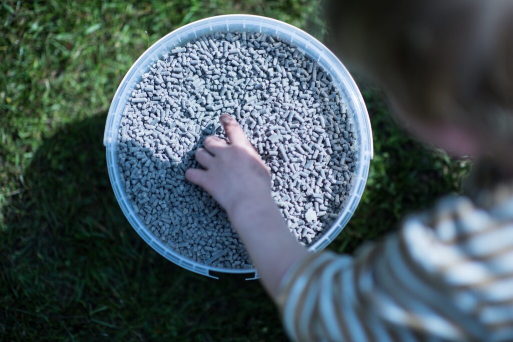Enfant prenant des granulés d'engrais dans un bac pour le gazon