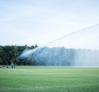 Beregeningshaspel sproeit water over een groot grasmattenveld