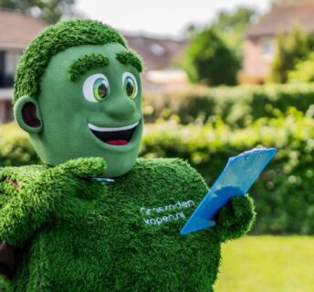 Mascotte Grasmattie met clipboard geeft tips voor het leggen van grasmatten