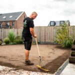 Medewerker egaliseert de ondergrond zorgvuldig ter voorbereiding op het leggen van grasmatten.