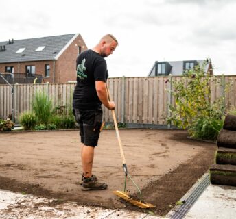 Medewerker egaliseert de ondergrond zorgvuldig ter voorbereiding op het leggen van grasmatten.