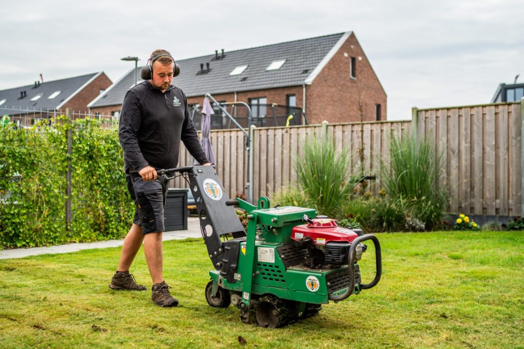 Medewerker van Graszodenkopen.be verwijdert oud gras met een snijmachine als voorbereiding op het leggen van nieuwe grasmatten.