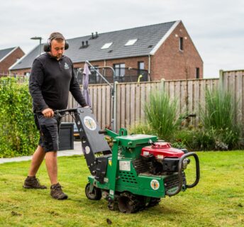 Medewerker van Graszodenkopen.be verwijdert oud gras met een snijmachine als voorbereiding op het leggen van nieuwe grasmatten.