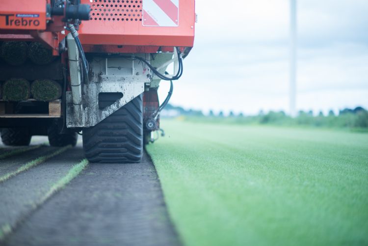 Close-up van een machine die grasmatten snijdt tijdens het oogsten