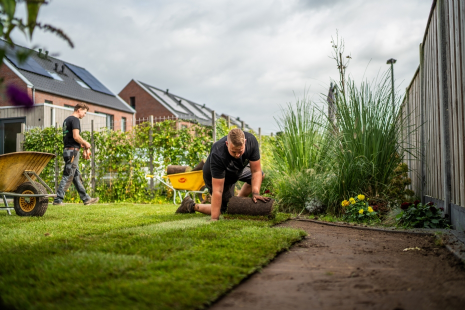 Medewerker die grasmatten uitrolt in tuin