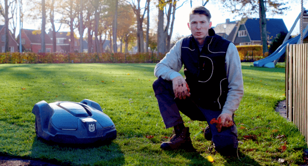Een gazon in het voorjaar met een robotmaaier waarbij uitleg wordt gegeven door een tuinaannemer